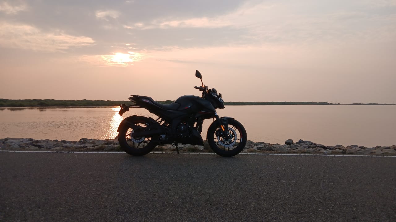 Motorcyclists riding along a coastal cliff at sunset